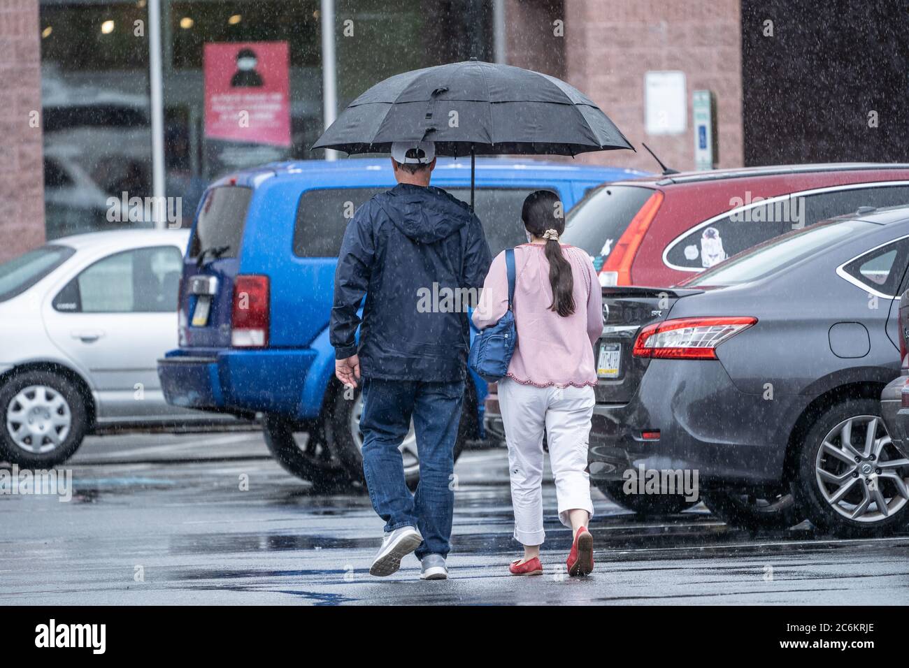 Couple marche dans le stationnement de l'épicerie sous la pluie. Banque D'Images