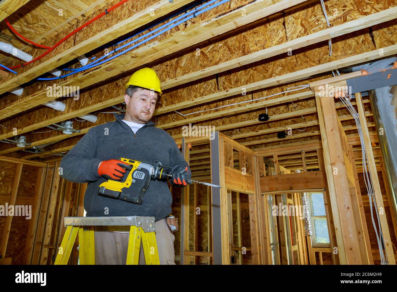 Cadre intérieur d'une nouvelle maison en construction ouvrier fore le trou de plafond avec le bois le câblage électrique Banque D'Images