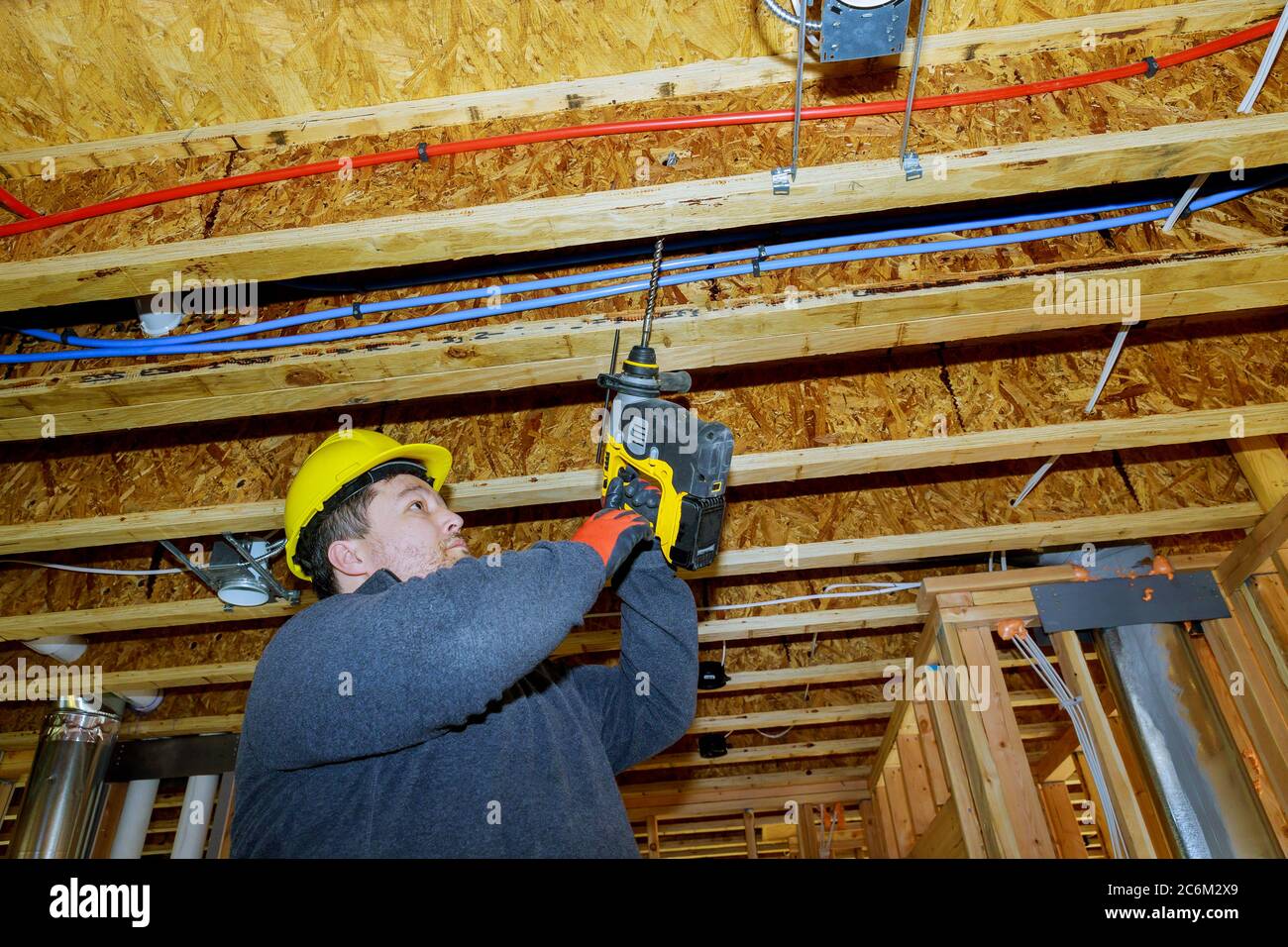 Le travailleur du constructeur fore le trou d'outil avec plafond en bois le cadre de la poutre de cadre de câblage électrique construit cadre Banque D'Images