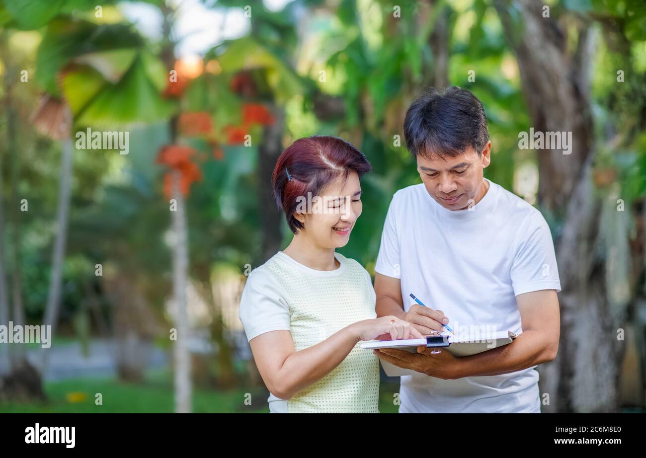 Un couple asiatique d'âge moyen parle et conçoit le plan de jardin ensemble dans l'arrière-cour. Banque D'Images