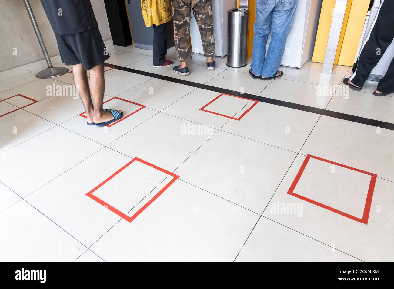 Les personnes pratiquant la distanciation sociale dans la file d'attente vers la machine de guichet automatique dans la banque pour transaction Banque D'Images