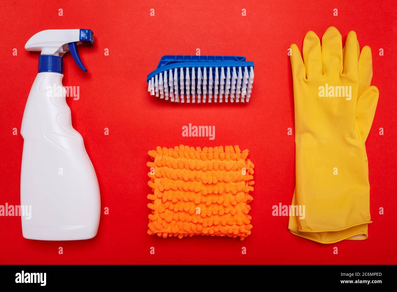 gants et brosses blancs et chiffon à balai sur fond rouge. CopySpace Banque D'Images