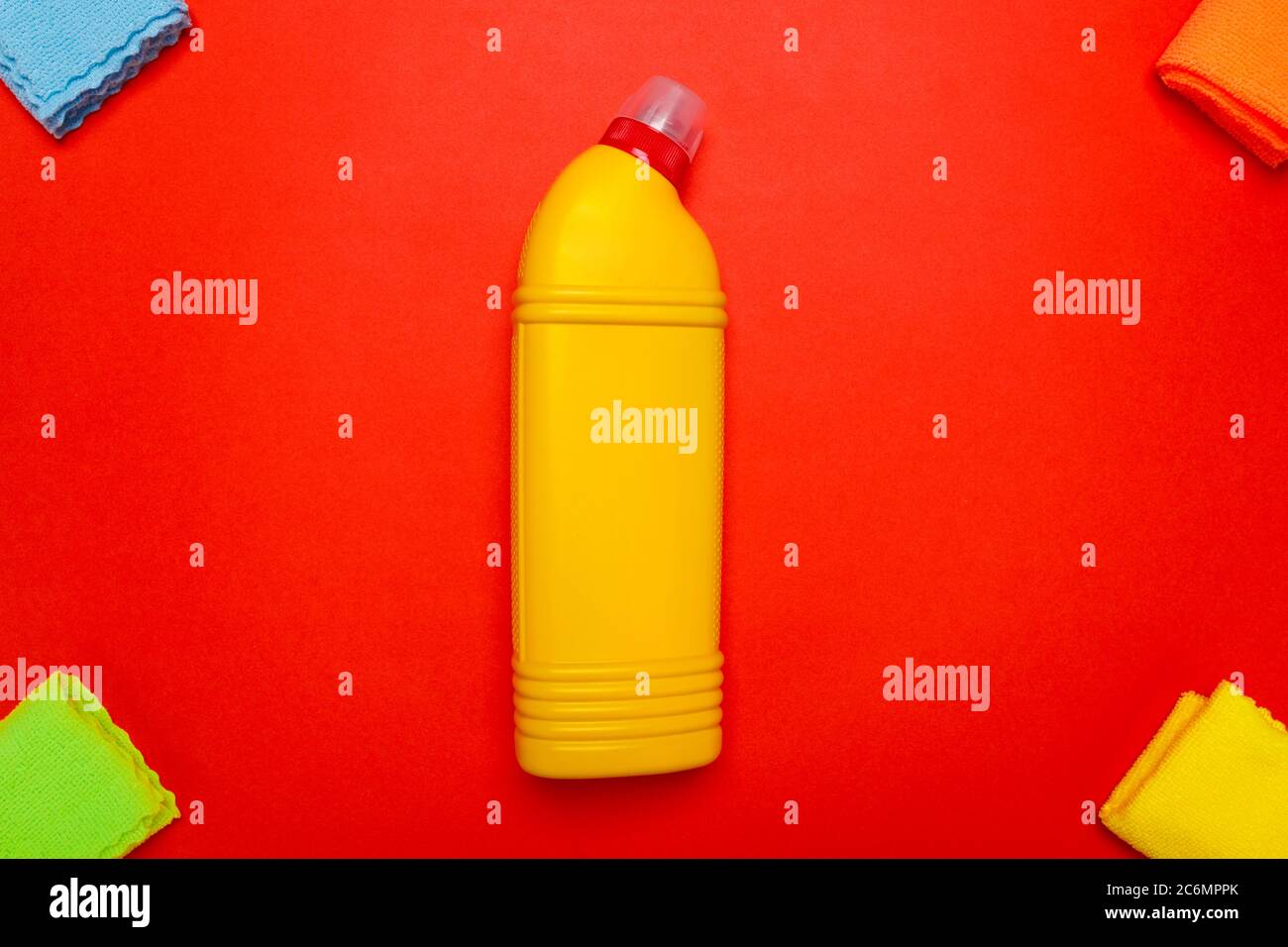 nettoyant pour toilettes jaune avec chiffons sur fond rouge. Banque D'Images