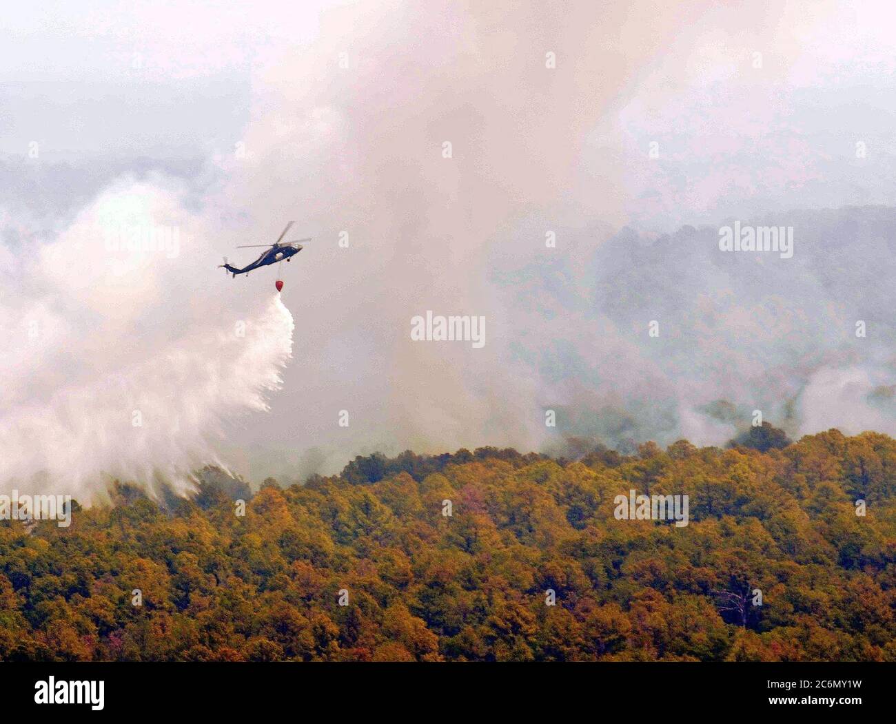 La Garde nationale du Texas un hélicoptère Blackhawk UH-60 antenne provenant de la distribution de l'eau Lutte contre l'incendie seau, connu sous le nom de 'Bambi', godet sur les flammes dans le centre du Texas Hill Country le Texas les équipages de la Garde nationale lancé à partir de l'Austin Army Aviation mondial à lutter contre les incendies de maisons et de biens menaçant près de Bastrop, Texas, le 6 septembre 2011. Depuis 1975, le ministère de l'Agriculture et Ministère de l'Intérieur ont eu un accord interorganisations avec le ministère de la Défense (DOD) qui permet de fournir l'appui du Département de la lutte contre les incendies à l'organismes de gestion des feux de lor Banque D'Images