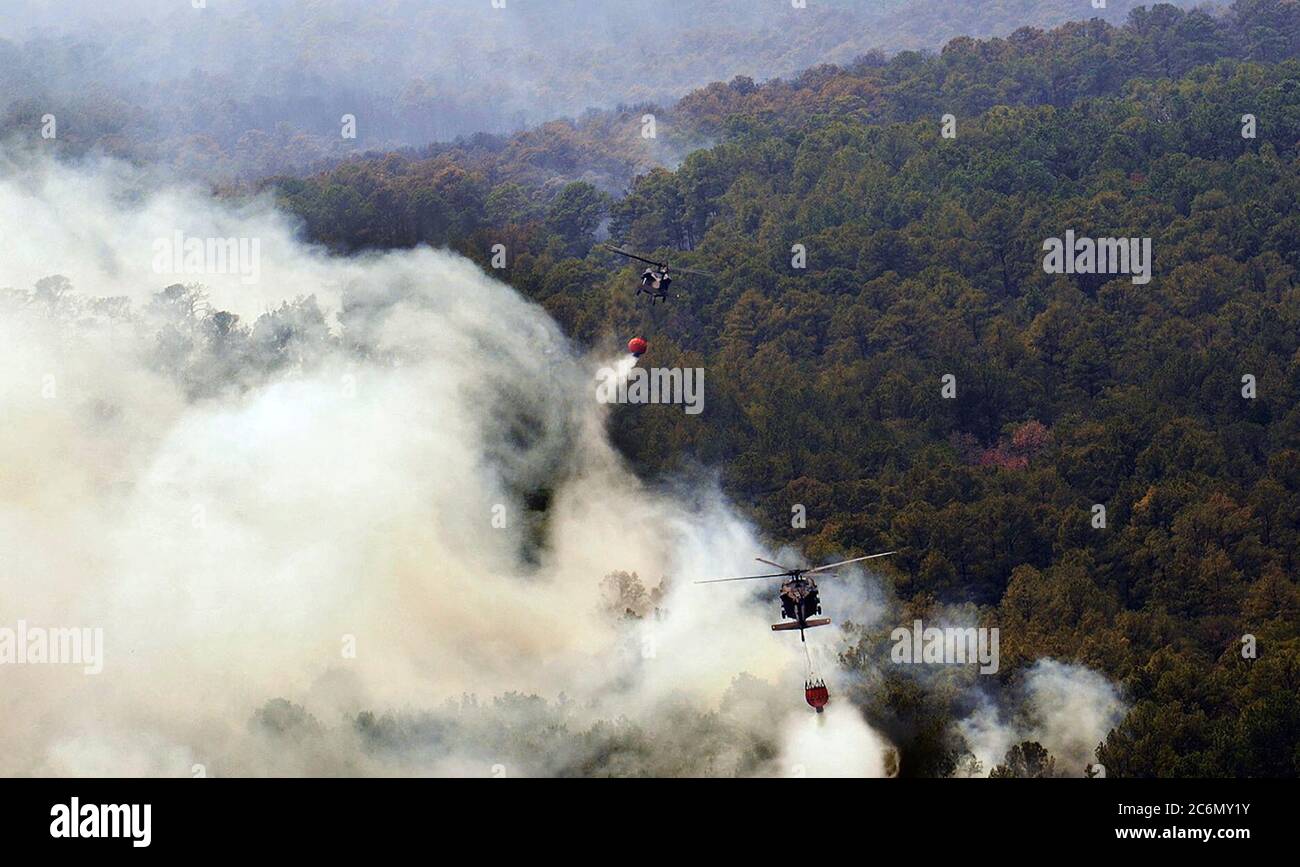 Deux hélicoptères Blackhawks UH-60 de la Garde nationale du Texas survolent les flammes pour évacuer l'eau des seaux de livraison d'eau de lutte contre les incendies aériens. Les équipes de la Garde nationale du Texas ont été lancées à partir de l'installation aérienne de l'armée d'Austin pour combattre les incendies de forêt menaçant les maisons et les biens près de Bastrop, au Texas, le 6 septembre 2011. Depuis 1975, le Département de l'agriculture et le Département de l'intérieur des États-Unis ont conclu un accord interagences avec le Département de la défense (DOD) qui permet au Département de fournir un soutien en matière de lutte contre les incendies aux agences de gestion des incendies de forêt, au besoin. Depuis 1975, le département américain d'Agricult Banque D'Images