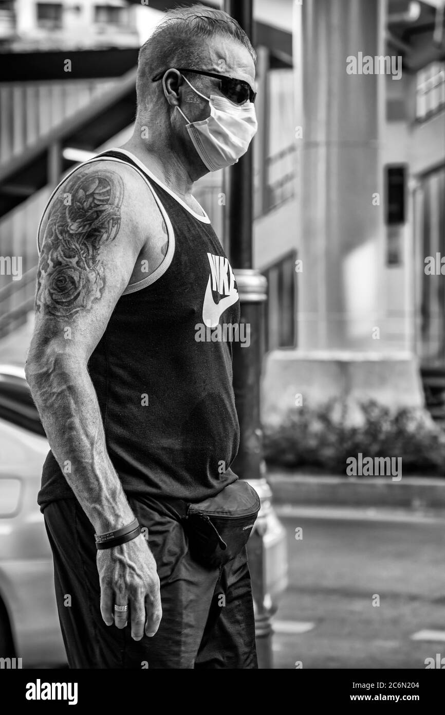 Homme caucasien portant un masque facial et tatouage dans la rue pendant la pandémie de Covid 19, Sukhumvit, Bangkok, Thaïlande Banque D'Images