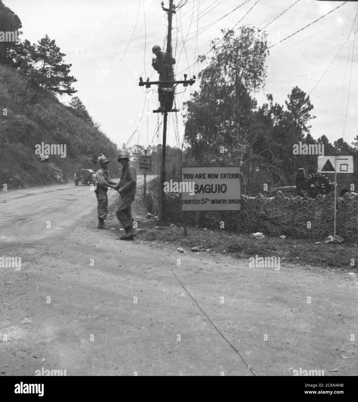 Un panneau indiquant « vous entrez maintenant dans Baguio, courtoisie 37e Division d’infanterie » salue les soldats de la 33ème Division d’infanterie alors qu’ils entrent à Baguio, Luzon, aux îles Philippines, le 27 avril 1945 Banque D'Images