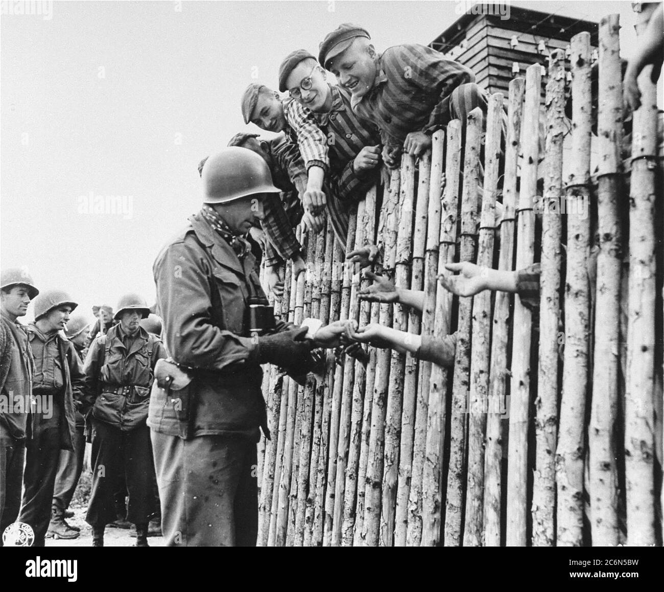 Le caporal Larry Matinsk de l'armée américaine met des cigarettes dans les mains étendues de prisonniers nouvellement libérés derrière un stock dans le camp de concentration d'Allach, près de Dachau Allemagne, le 30 avril 1945. On trouve également sur la photo les soldats américains Arthur Toratti et George Babel (deuxième et troisième à partir de la gauche). Allach était un sous-camp du camp de concentration de Dachau. Des soldats américains de la 7e Armée des États-Unis, y compris des membres de la 42e infanterie et de la 45e infanterie et de la 20e division des soldats de l'armée, ont participé à la libération de l'subcamp. Le principal camp de concentration de Dachau comptait plus de 120 sous-camps dans la région Banque D'Images