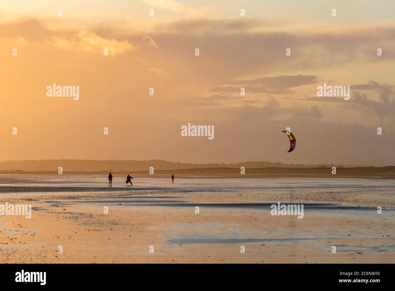 Kiteboarder sur Camber Sands, East Sussex au coucher du soleil. Banque D'Images