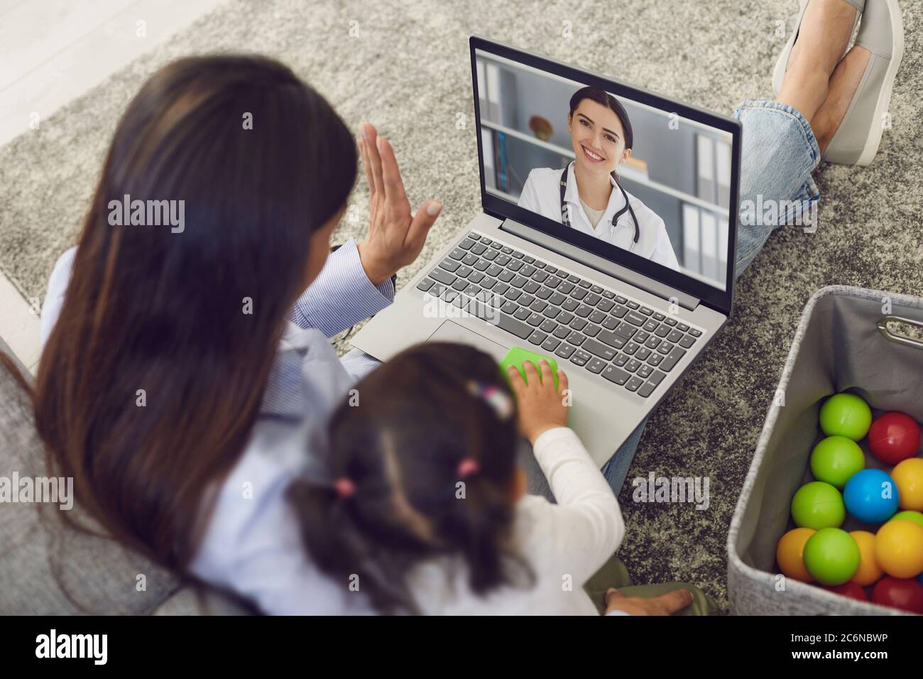 Médecin de famille en ligne. La mère et le bébé saluent le médecin ayez un ordinateur portable d'appel vidéo pour le médecin à la maison. Banque D'Images