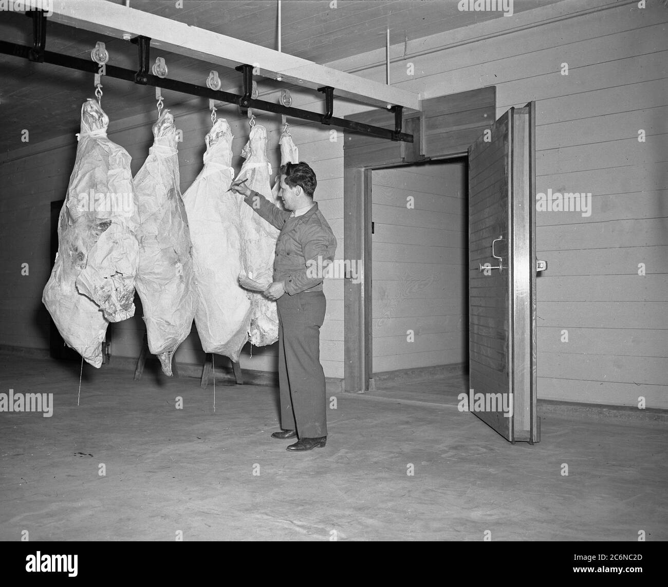 Un soldat inspecte la viande dans une zone d'entreposage frigorifique en décembre 1943 à l'époque Camp McCoy Banque D'Images