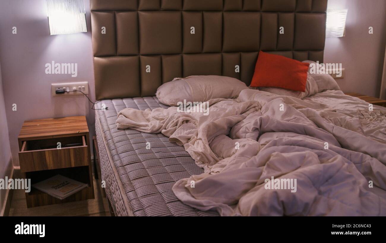 Un lit vide grondé dans l'hôtel. Couverture et oreillers froissés. Gros plan sur un lit désordonné. Draps, draps et oreillers usagés après avoir dormi dans la nuit Banque D'Images