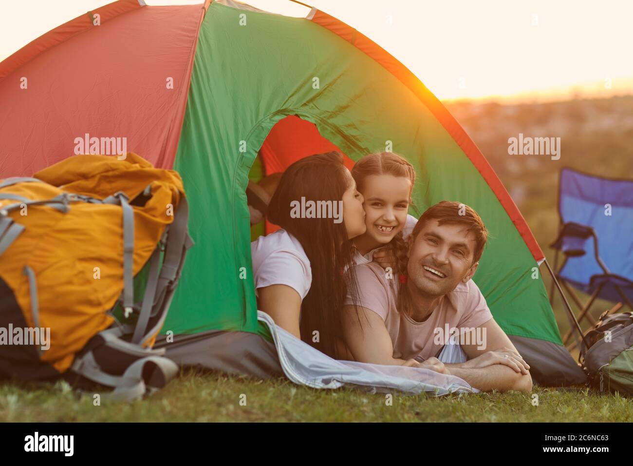 Famille heureuse avec enfant en voyage de camping se détendre à l'intérieur de la tente. Banque D'Images