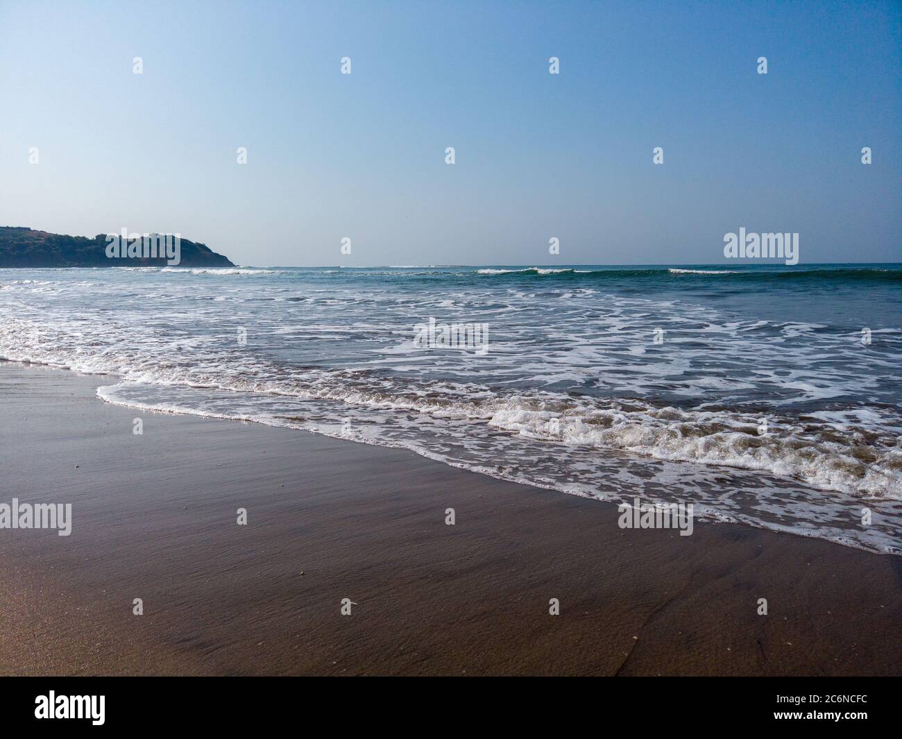Vagues de mer mousseuse sur le rivage. Vagues d'eau de mer propre sur une plage de sable humide le jour de soleil sur la station Banque D'Images