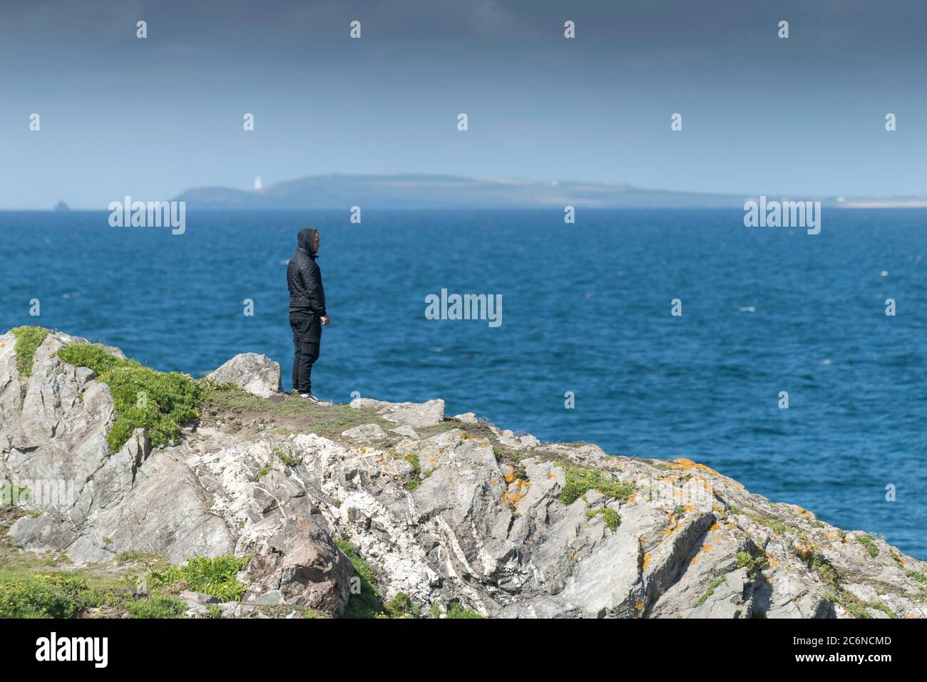 Un homme debout sur des rochers de Towan Head, qui regarde dans la baie de Newquay, dans les Cornouailles. Banque D'Images