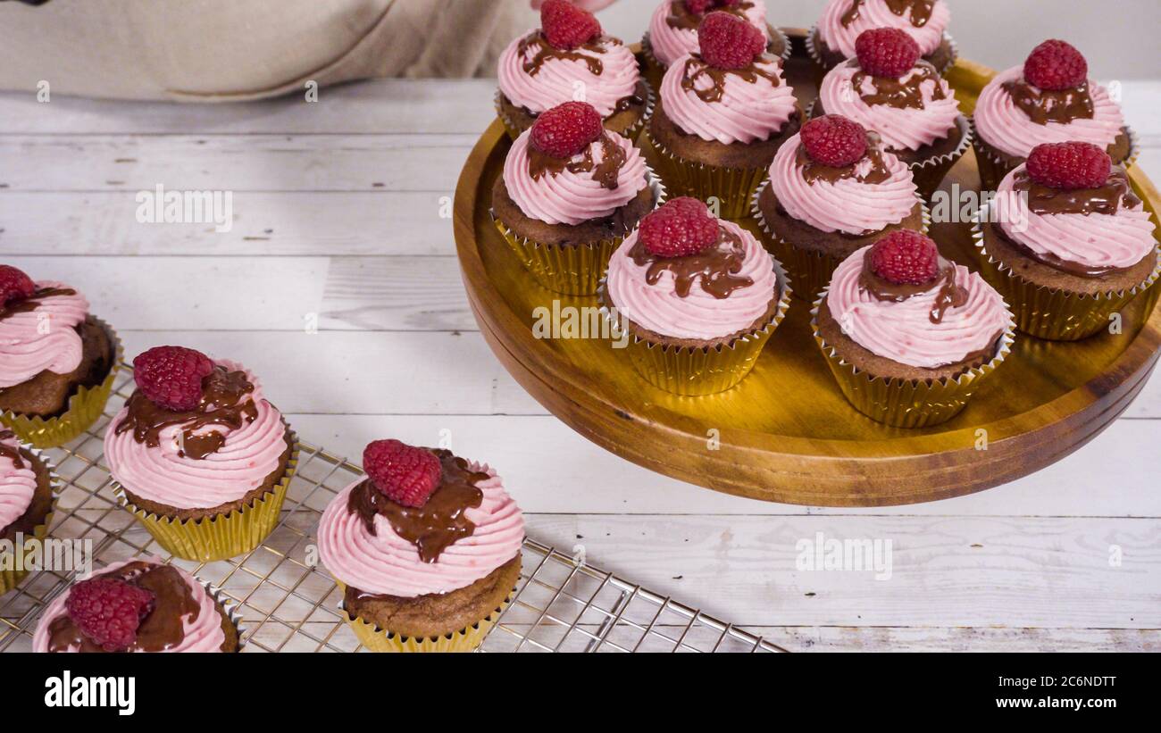 Des cupcakes au chocolat gourmets, arrosés de ganache au chocolat et recouverts d'une framboise fraîche. Banque D'Images