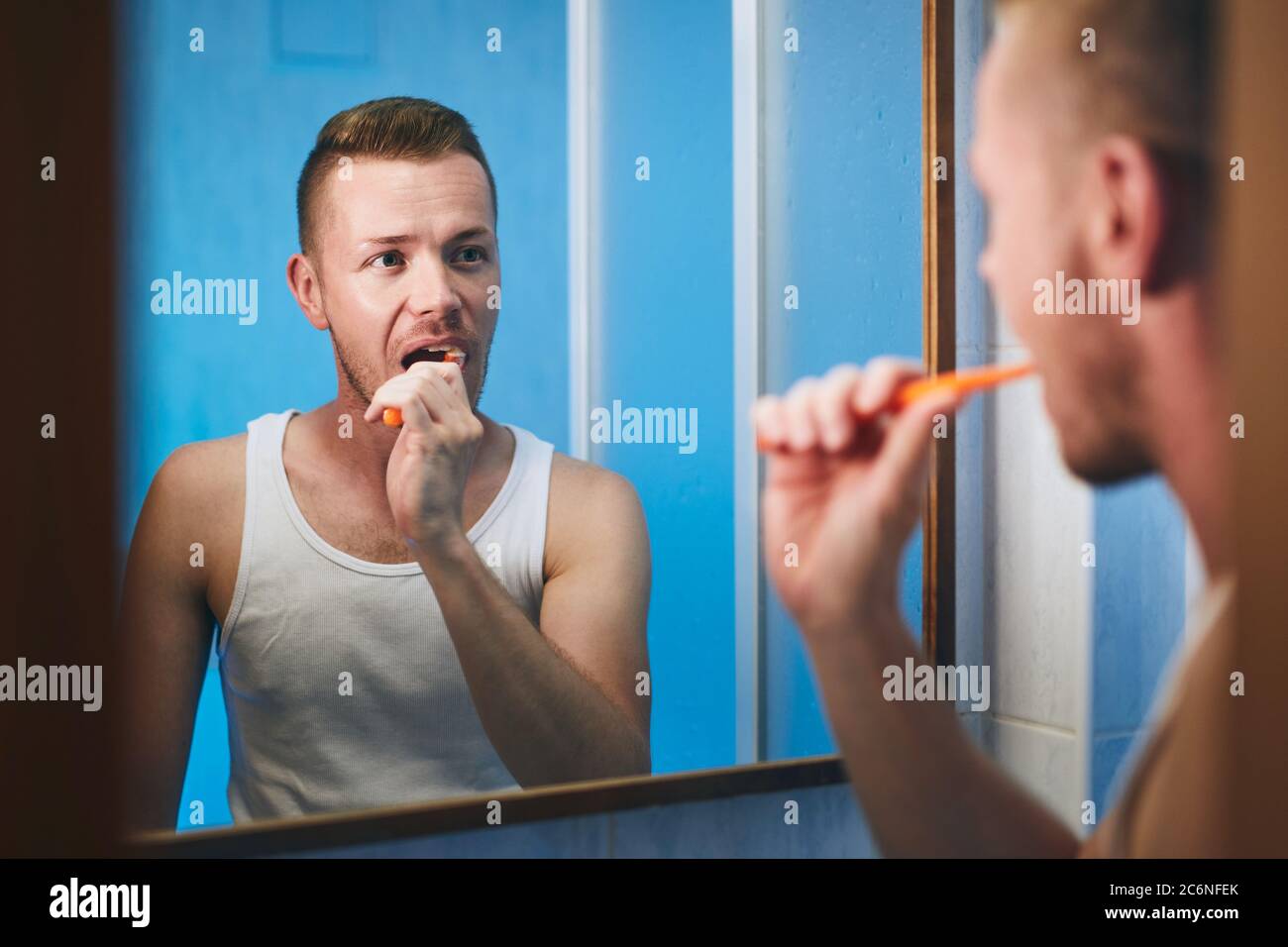 Routine d'hygiène du matin. Homme se brossant les dents et regardant dans le miroir de la salle de bains de la maison. Banque D'Images