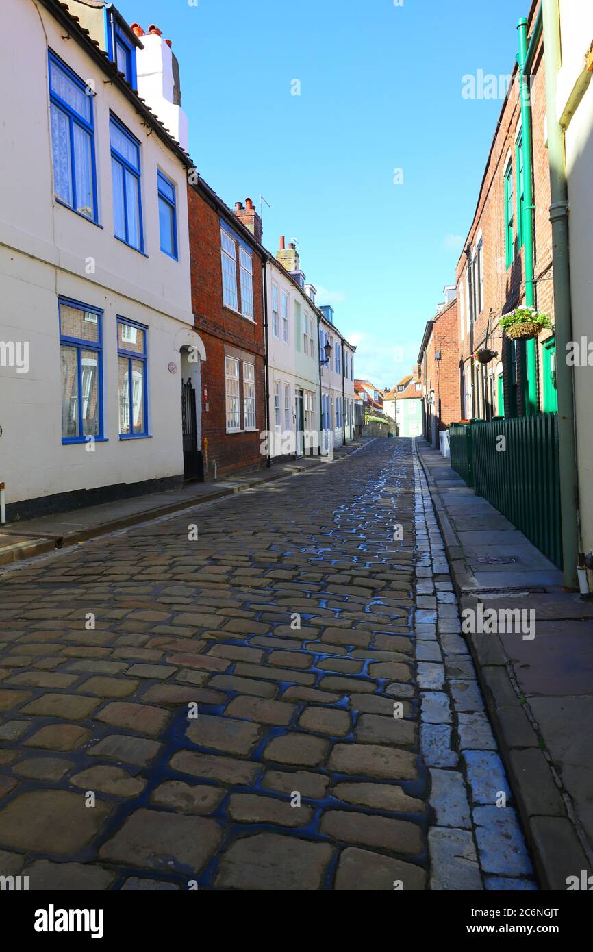 Rue pavée avec ciel bleu et maisons en terrasse à Whitby, North Yorkshire, Angleterre, Royaume-Uni Banque D'Images
