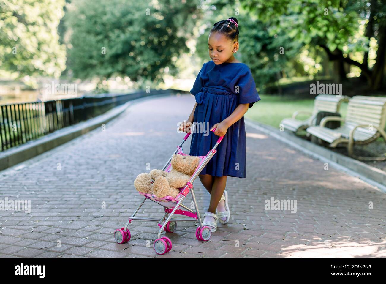 Belle Petite Fille Africaine En Robe Bleue Joue Avec L Ours En Peluche Jouet Assis Dans La Poussette De Petit Enfant Marchant Dans Le Beau Parc De La Ville Photo Stock Alamy