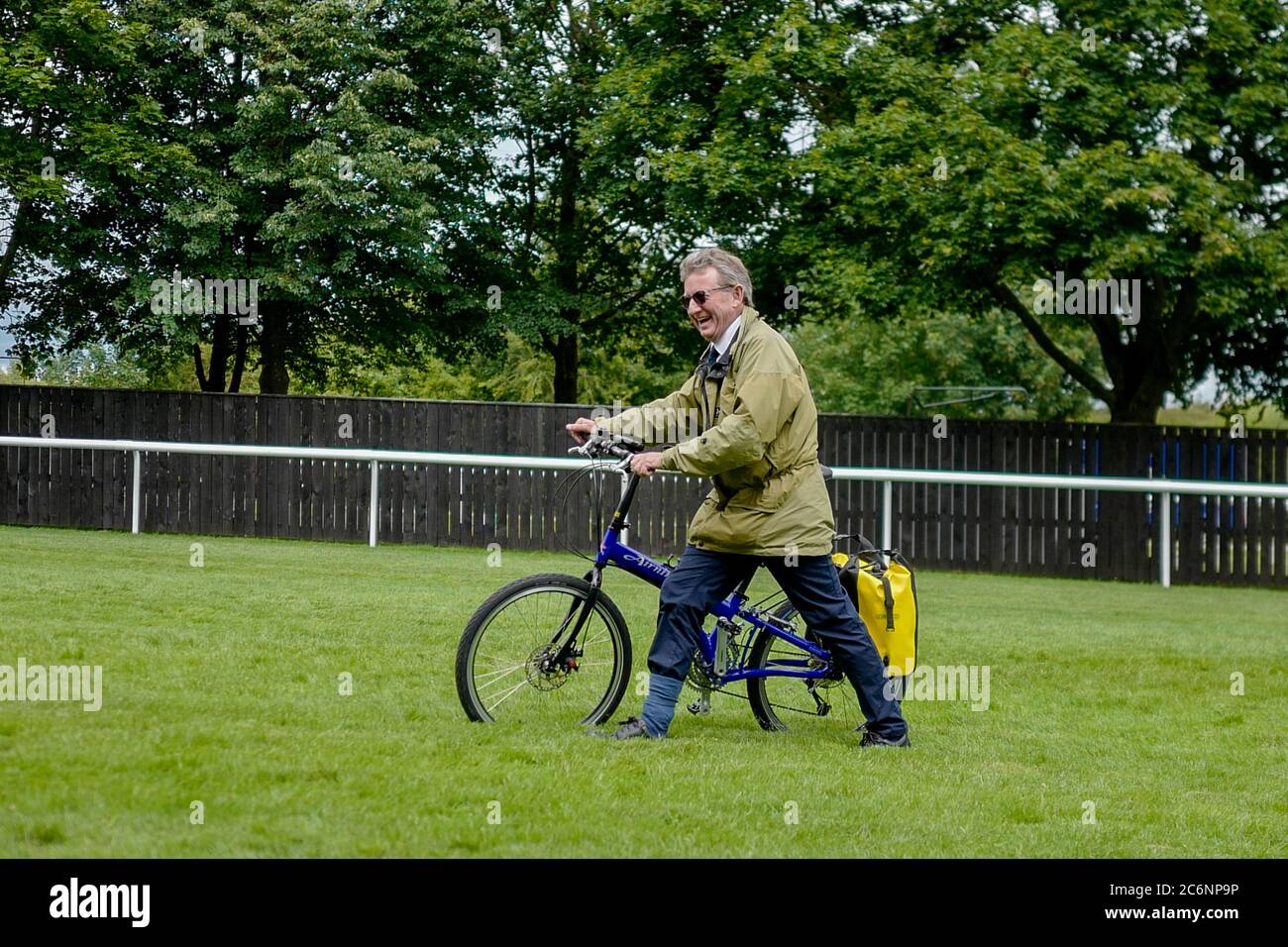 L'entraîneur Mark Johnston arrive sur le parcours avec son vélo après avoir atterri son avion plus loin dans les enceintes et a parcouru les tribunes le troisième jour du festival de juillet Moet et Chandon à l'hippodrome de Newmarket. Banque D'Images