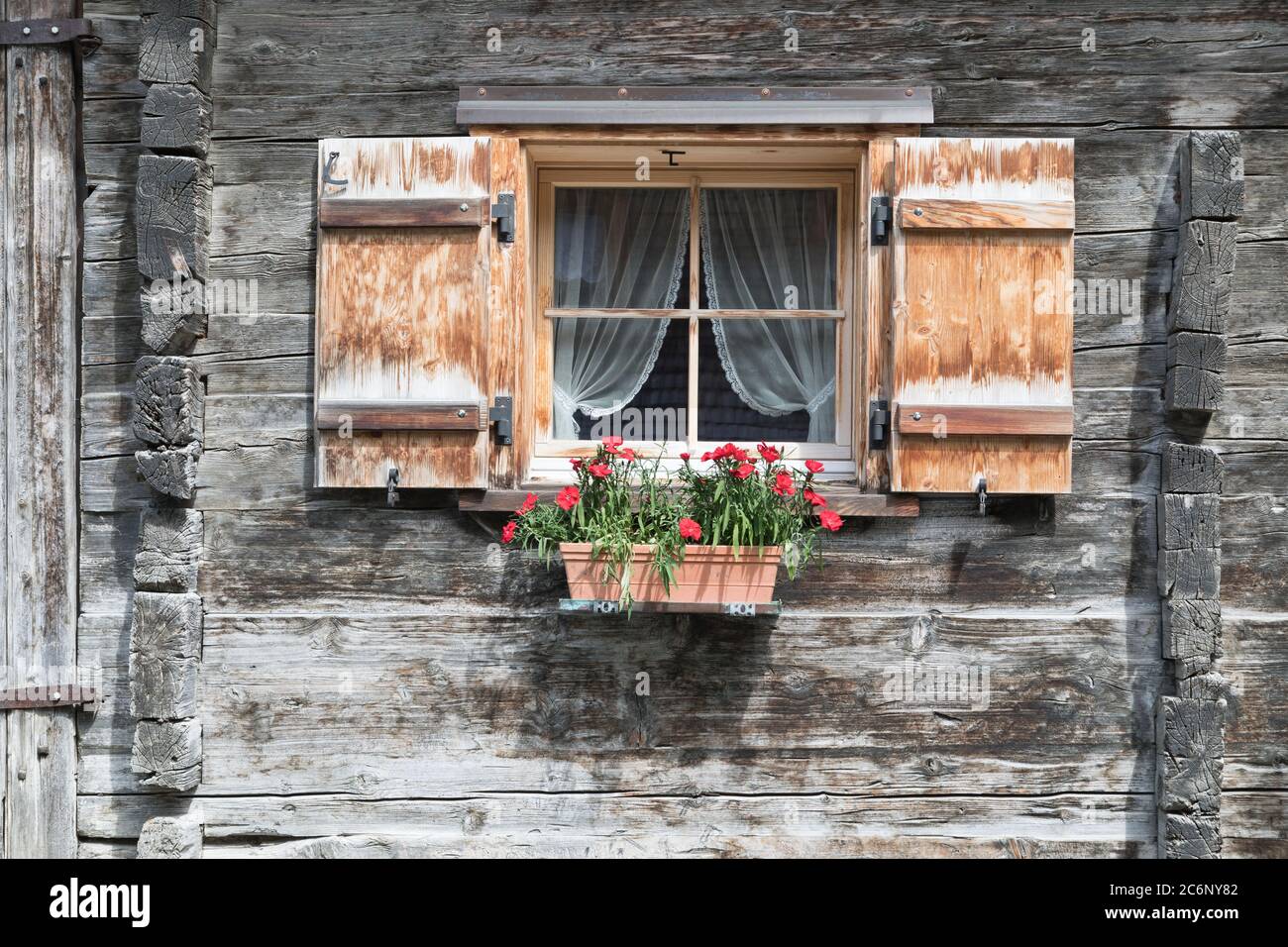 fenêtre avec volets et fleurs dans le bois gris Banque D'Images