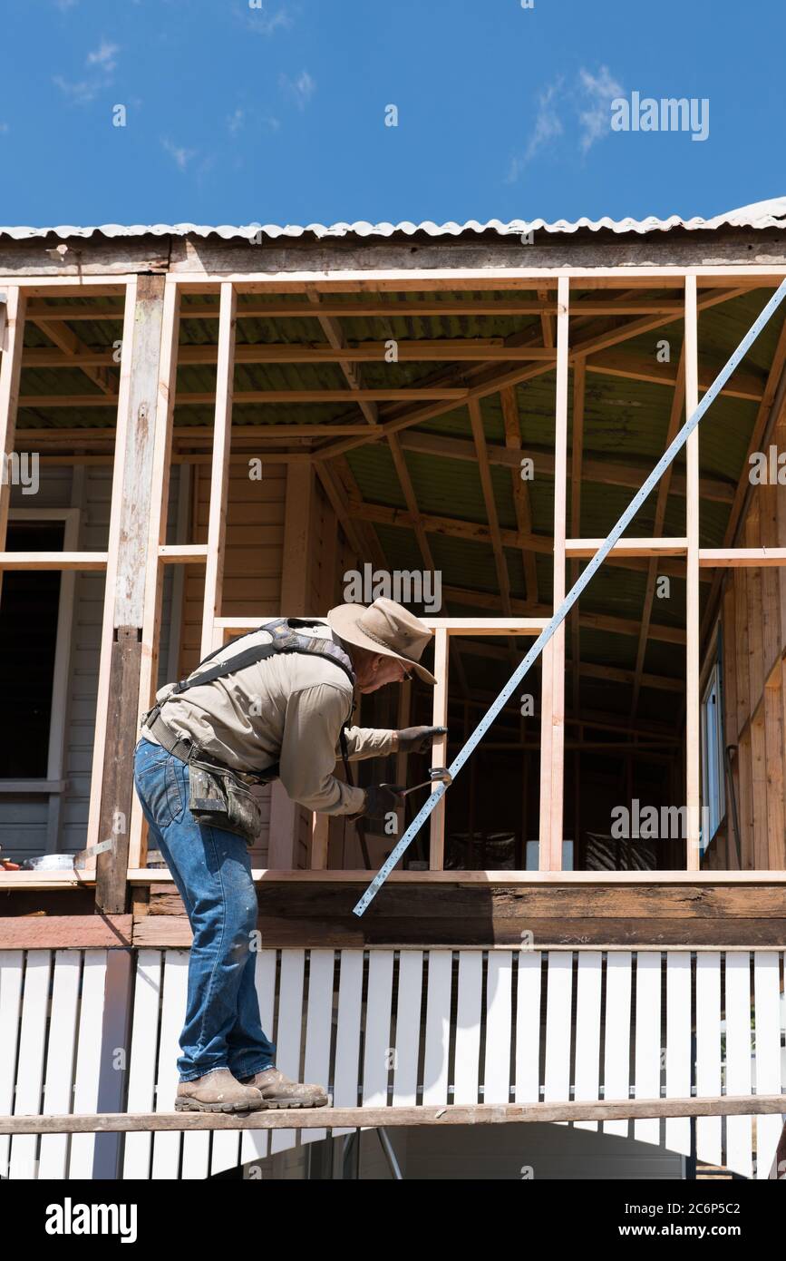 Menuisier travaillant sur l'ancien bois encadré haut style Queenslander maison pendant les rénovations Banque D'Images