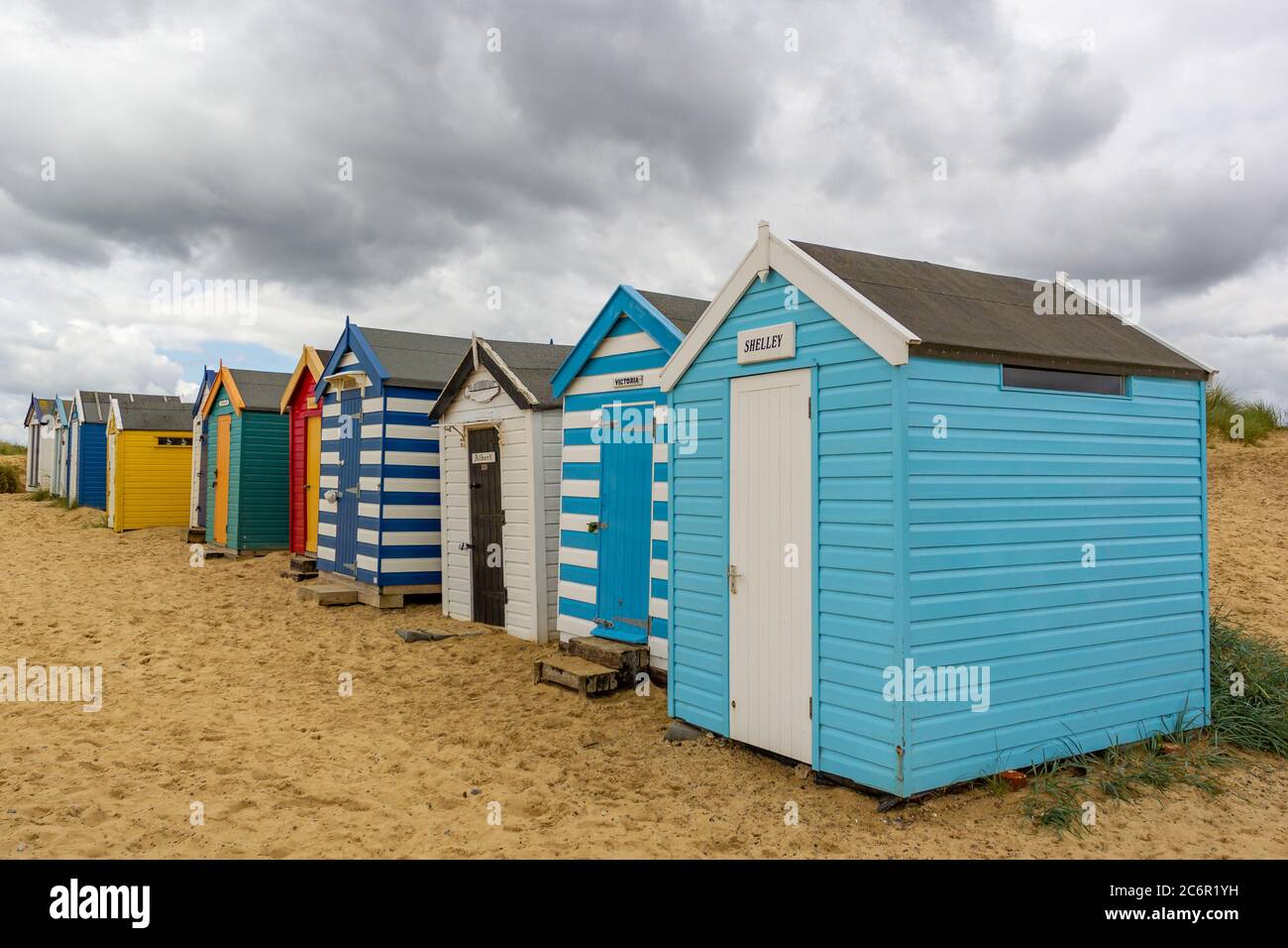 Une ligne de cabanes de plage sur une plage de sable en dessous un ciel spectaculaire Banque D'Images