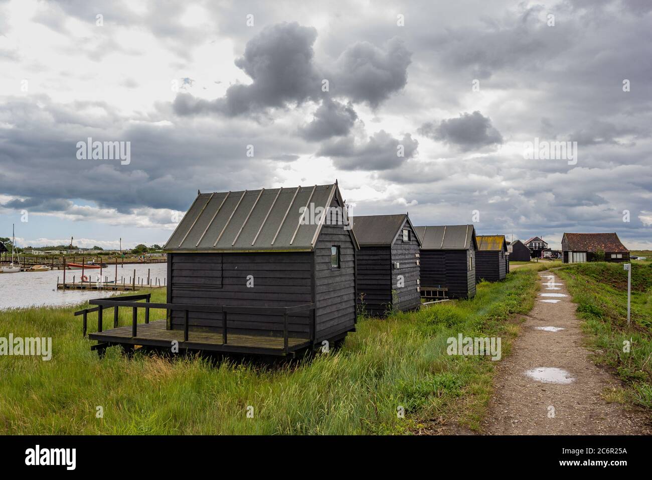 Cabanes de plage noires à Warbleswick sur le manteau Suffolk sous un ciel sombre et sombre Banque D'Images