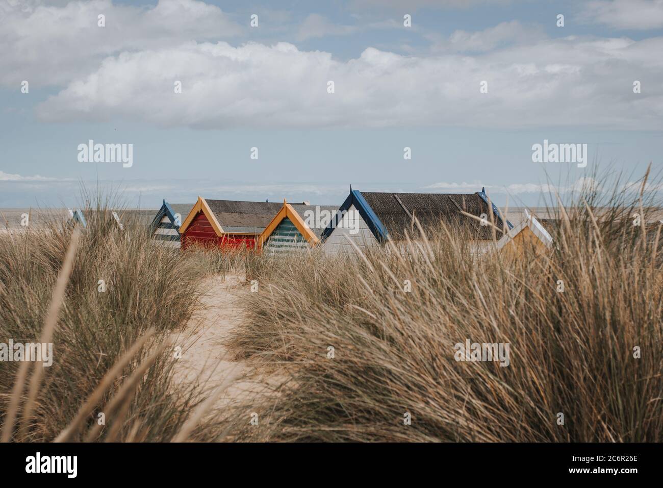 Une ligne de toits de hutte de plage à travers les longues dunes d'herbe et de sable Banque D'Images