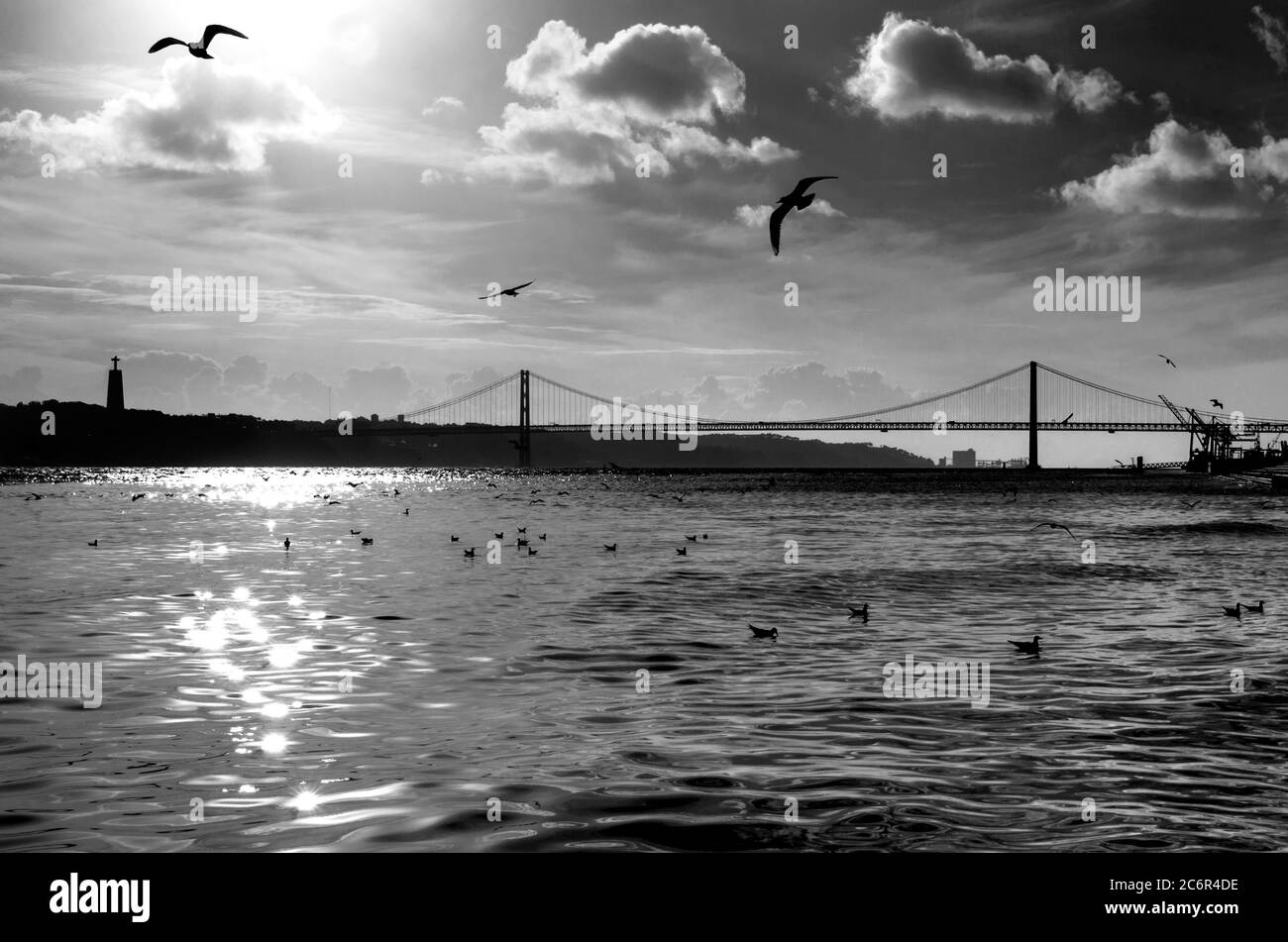 Le pont du 25 avril (Ponte 25 de Abril) traversant le Tage (Tejo), Lisbonne, Portugal. Paysage urbain artistique noir et blanc avec rivière et dramat Banque D'Images