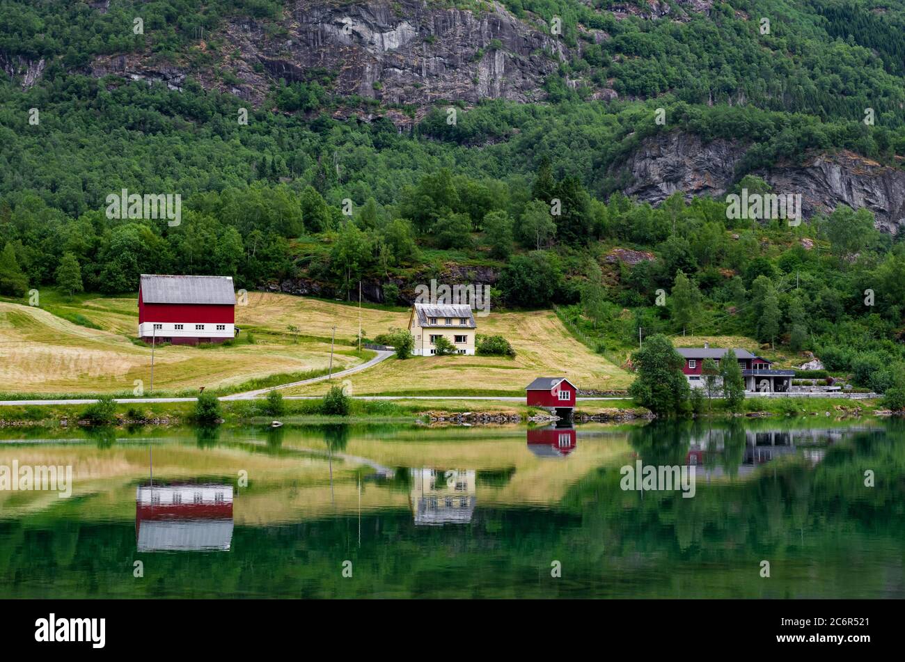 Magnifique paysage norvégien reflété dans le lac. Fermes, forêt, champs et montagnes sur une rive du lac de Floen, vallée d'Oldedalen, Norvège. Banque D'Images