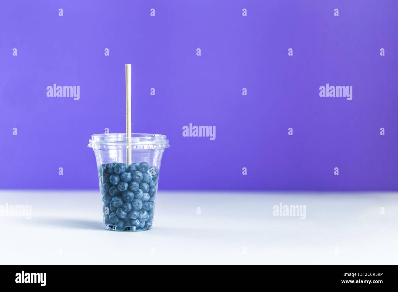 Bleuet dans la tasse en plastique smoothie avec une paille en papier Banque D'Images