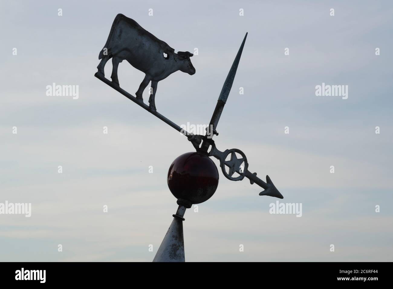 Une vieille girouette inclinée avec sculpture d'une vache laitière. Banque D'Images