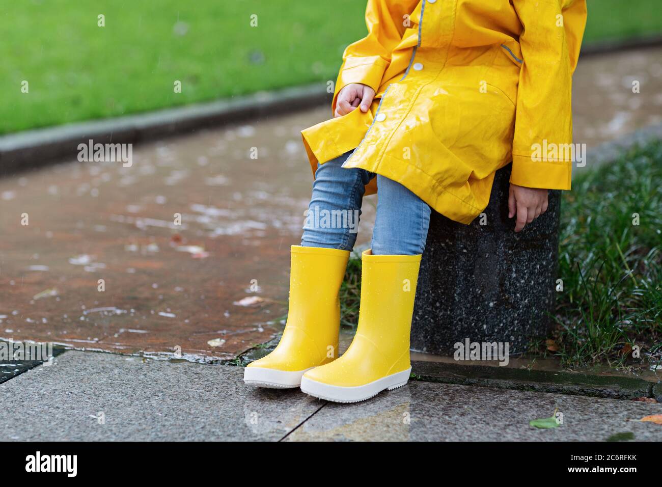 Jolie petite fille en imperméable jaune et bottes en caoutchouc marchant à  l'extérieur sous la pluie. Mauvais temps, tempête tropicale d'été, concept  de mode d'automne Photo Stock - Alamy
