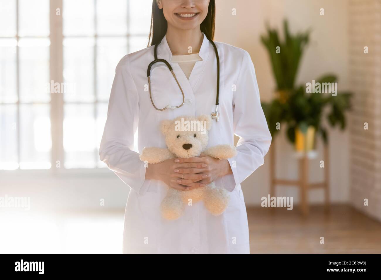 Gros plan médecin pédiatre souriant tenant le jouet moelleux dans les mains Banque D'Images