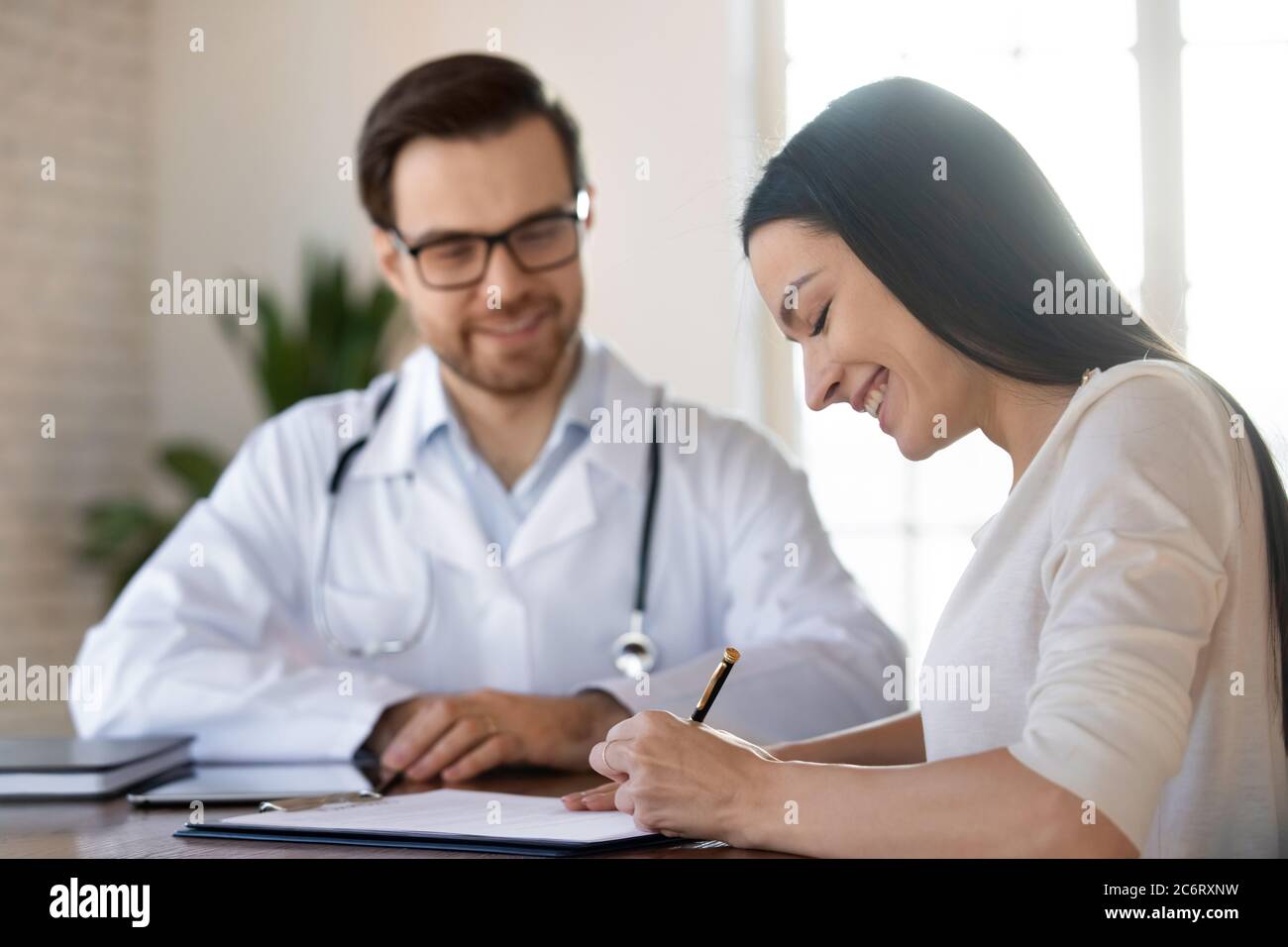 Femme souriante signant un contrat d'assurance dans une clinique Banque D'Images