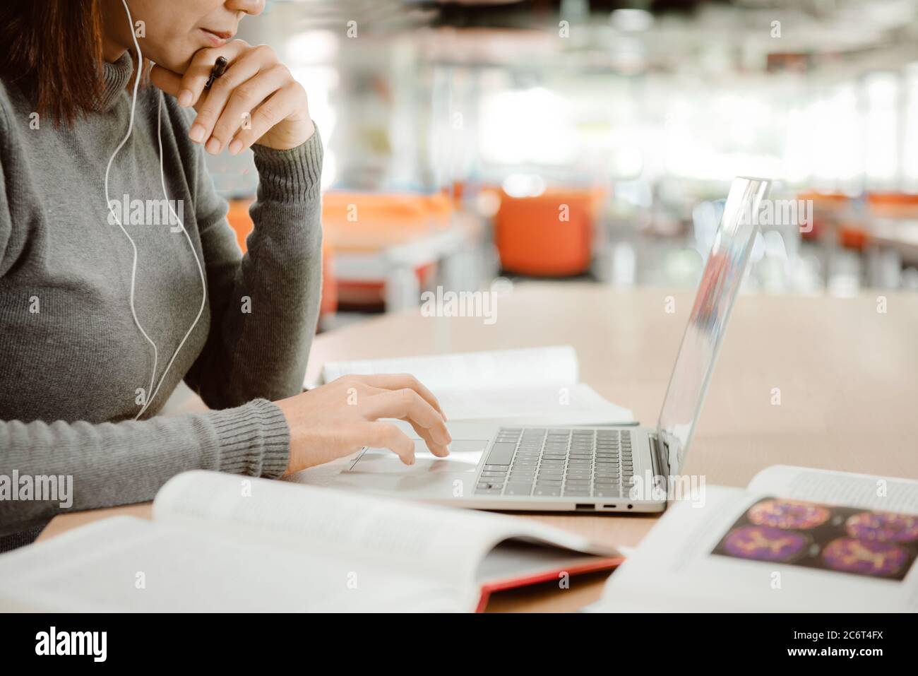 Une jeune fille étudiante avec un casque se préparant à l'examen et à l'utilisation d'un ordinateur portable tout en étant assise à la table de la bibliothèque de l'université. Banque D'Images
