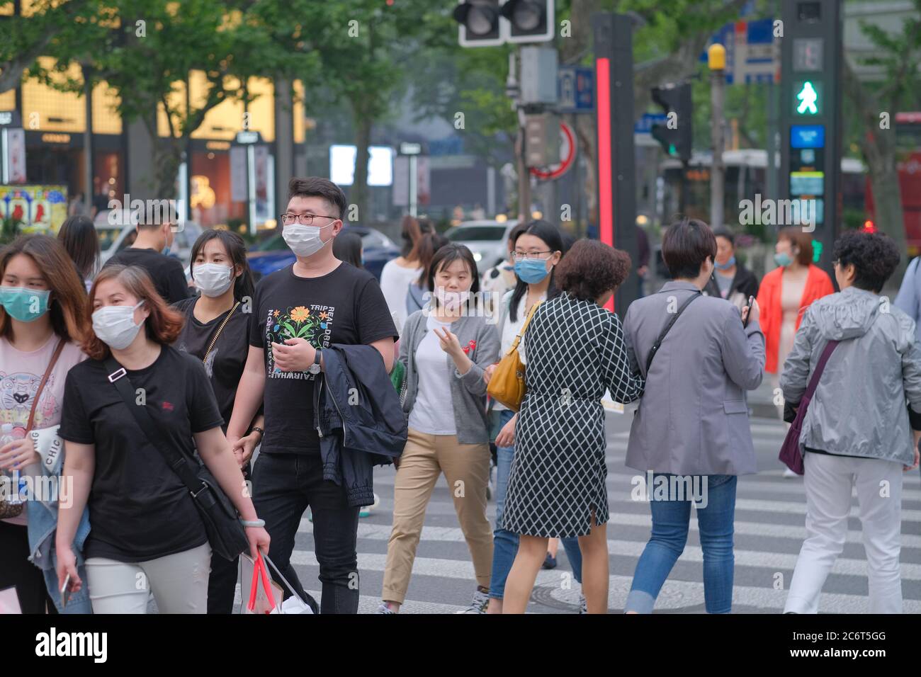 Les jeunes marchant sur le passage de zébra, portant un masque facial pour éviter le coronavirus Covid-19 Banque D'Images