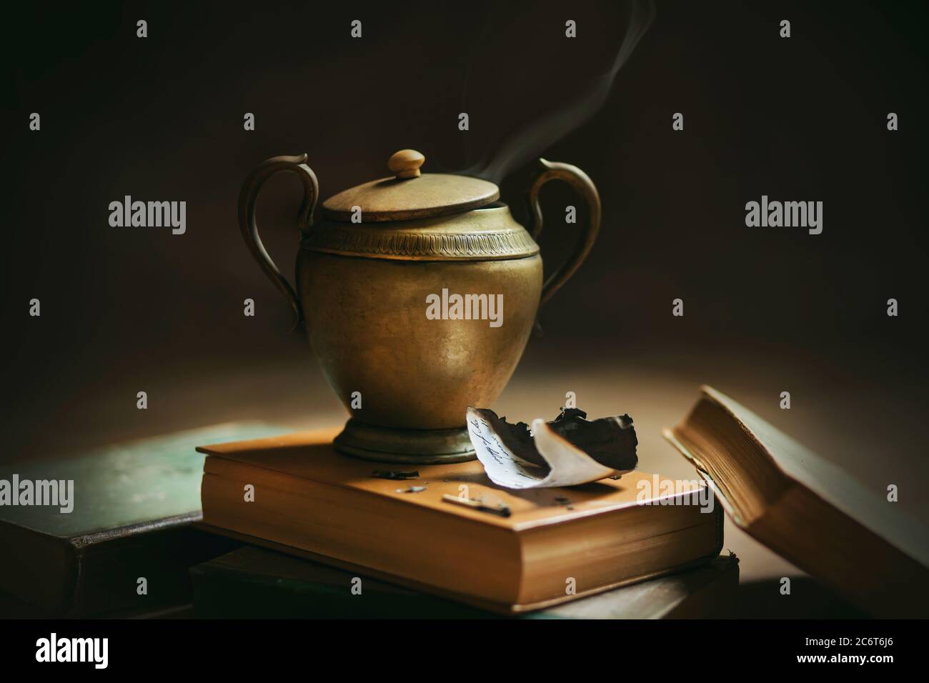 Encore la vie avec des choses anciennes - encyclopédies épaisses et une lampe en cuivre avec un ornement et avec un génie, d'où la fumée sort. Exécution des désirs Banque D'Images