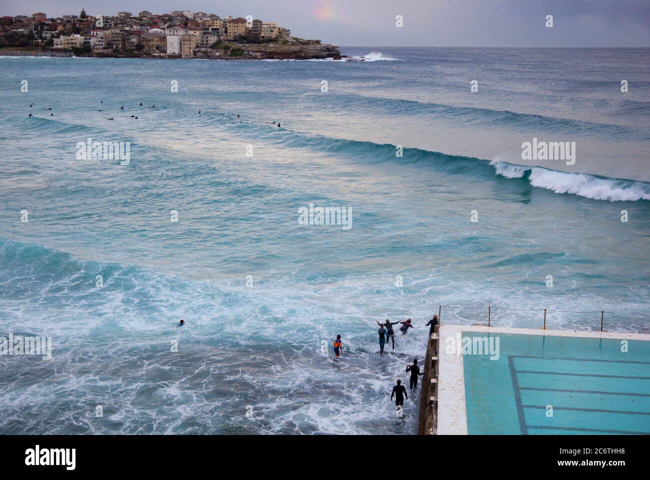Nageurs surfeurs en combinaison jouent sur les vagues près de la piscine sur la plage de Bondi Banque D'Images