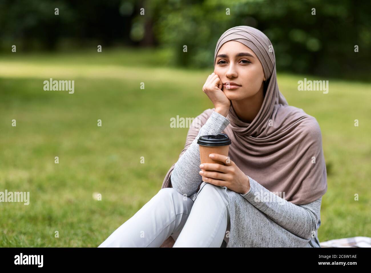 Contrarié arabe fille de boire du café seul au parc Banque D'Images