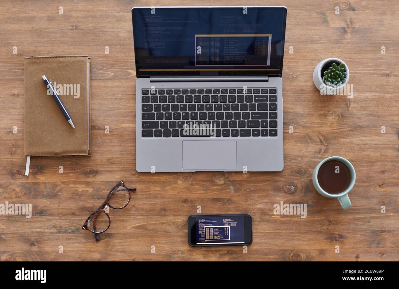 Vue de dessus en arrière-plan composition d'ordinateur portable et de smartphone avec code informatique sur bureau en bois texturé, espace de copie Banque D'Images