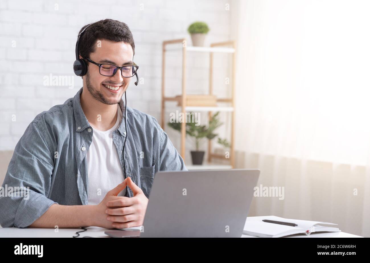 Apprendre l'anglais en ligne. Homme souriant avec un casque regardant un  ordinateur portable, parlant avec un professeur Photo Stock - Alamy