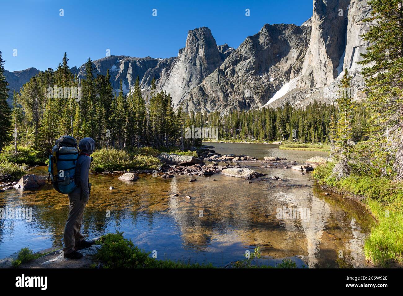 Un routard mâle voyageant sur le sentier North Fork s'arrête le long de la rivière North Popo Agie pour admirer la vue sur un lac et le cirque. Banque D'Images