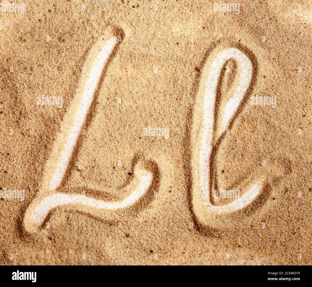 Lettre L. alphabet manuscrit anglais dans le sable. Banque D'Images