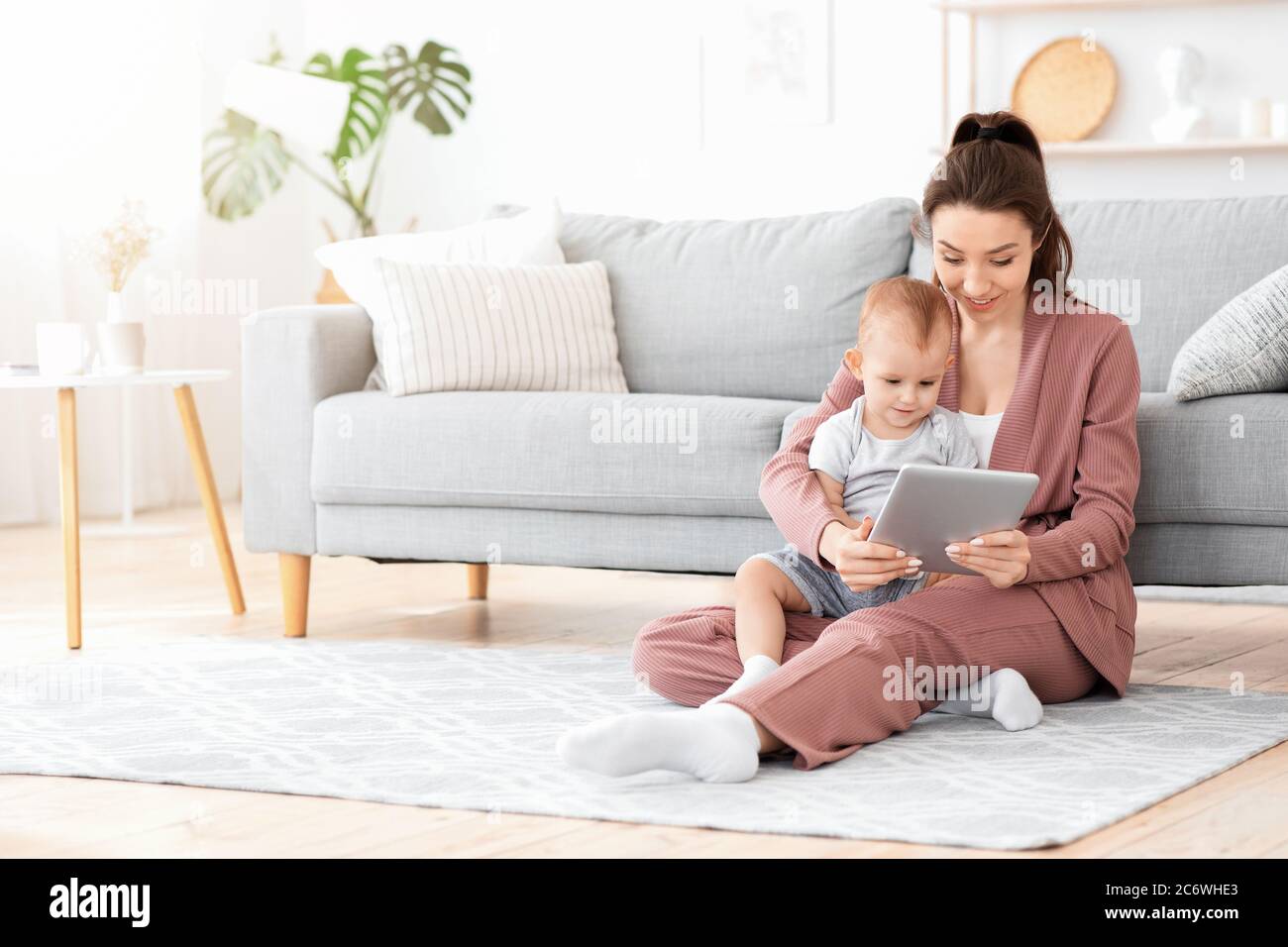 Une mère souriante et son adorable bébé regardent ensemble des caricatures sur une tablette numérique Banque D'Images