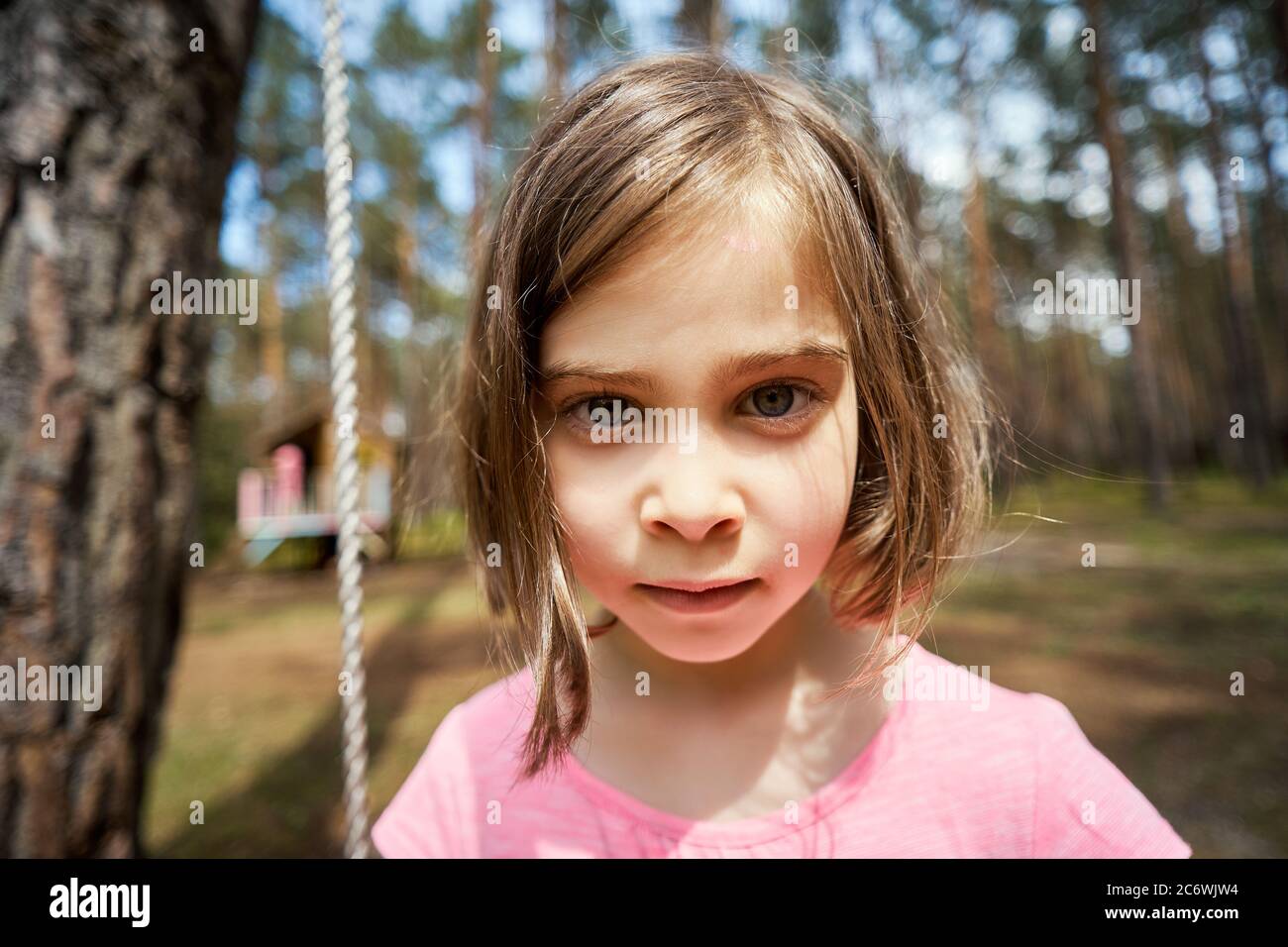 adorable petite fille s'assoit sur une balançoire et fait des visages Banque D'Images