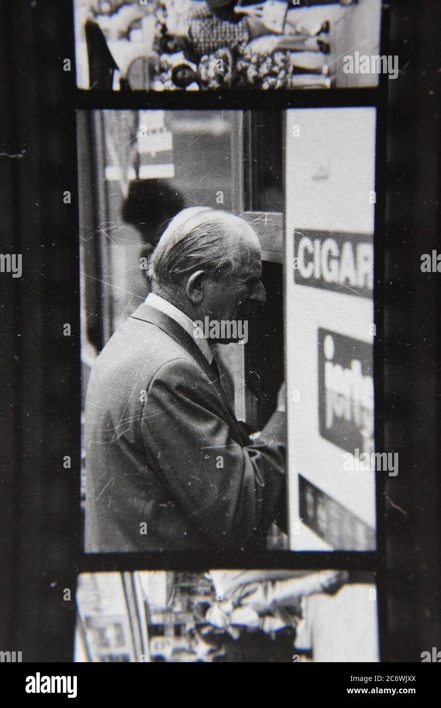 Fin années 70 vintage noir et blanc style de vie photographie d'un homme plus âgé achetant un cigare d'un vendeur de rue. Banque D'Images
