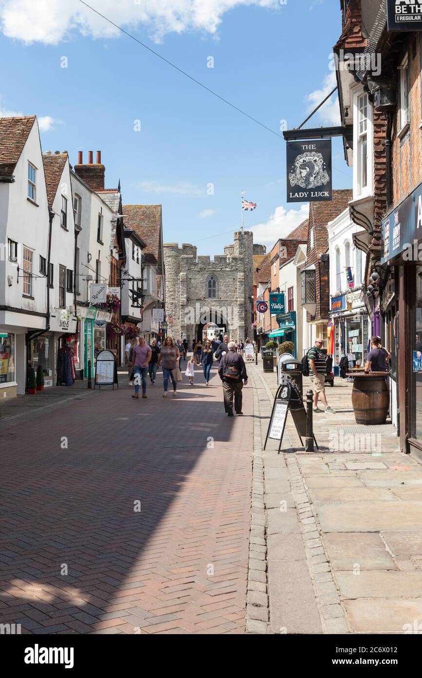 Extrémité nord de la rue High Street à Canterbury avec des acheteurs et une vue sur les tours médiévales de Westgate. Banque D'Images