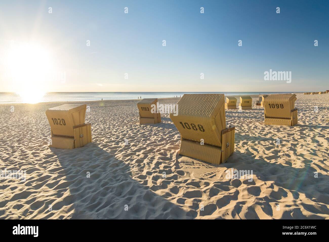 De nombreuses chaises de plage à l'océan avec des reflets panoramiques de lentille pendant le beau coucher de soleil sur l'île de Sylt en Allemagne Banque D'Images